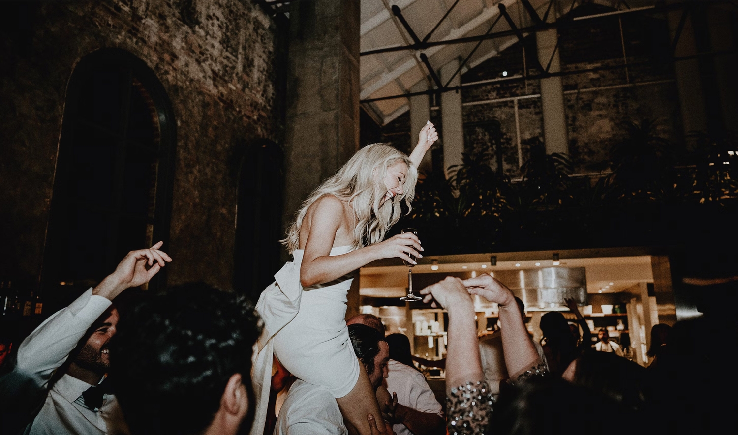 Bride lifted onto shoulders at a Darling Group event inside a high-ceilinged venue